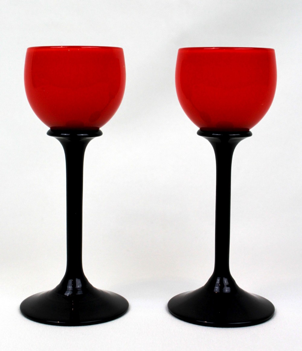 A pair of Art Deco Tango liqueur glasses featuring bright red rounded bowls supported by slender black stems and flat circular black bases. View IV