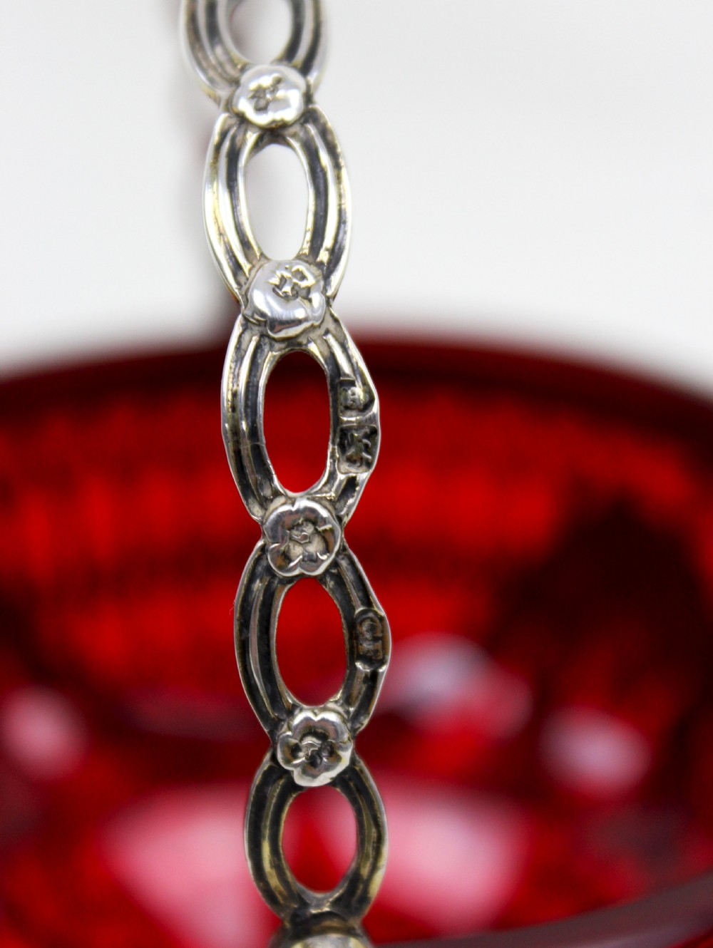 A Victorian silver-gilt sugar basket featuring elaborate pierced openwork, floral swags, a swing handle, and a removable ruby red glass liner. View VII