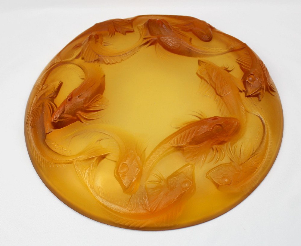 An Art Deco amber glass shallow dish featuring a relief motif of swimming fish radiating around the centre. View IV