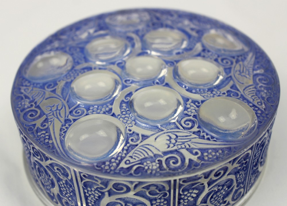 A circular Art Deco blue-stained glass powder box featuring moulded relief patterns of birds, grapevines, and polished glass cabochons. View III