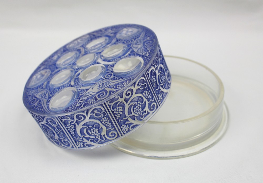 A circular Art Deco blue-stained glass powder box featuring moulded relief patterns of birds, grapevines, and polished glass cabochons. View IV