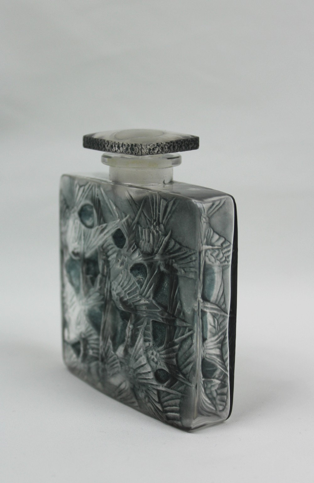 A rectangular frosted glass perfume bottle featuring relief carvings of flying swallows and a matching flat stopper. View II
