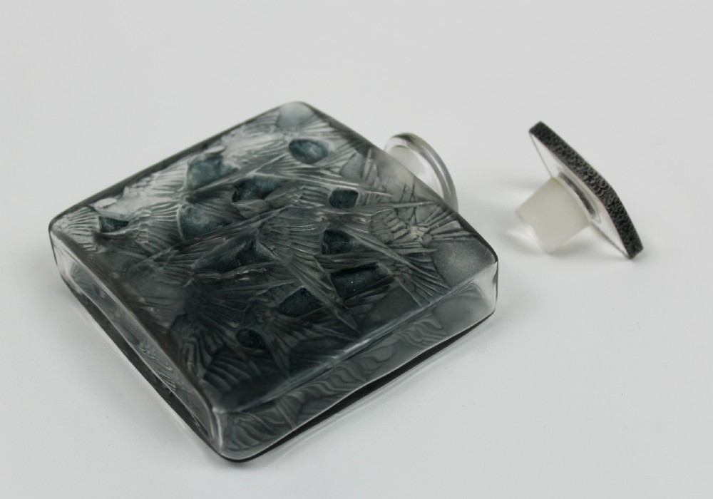 A rectangular frosted glass perfume bottle featuring relief carvings of flying swallows and a matching flat stopper. View IV