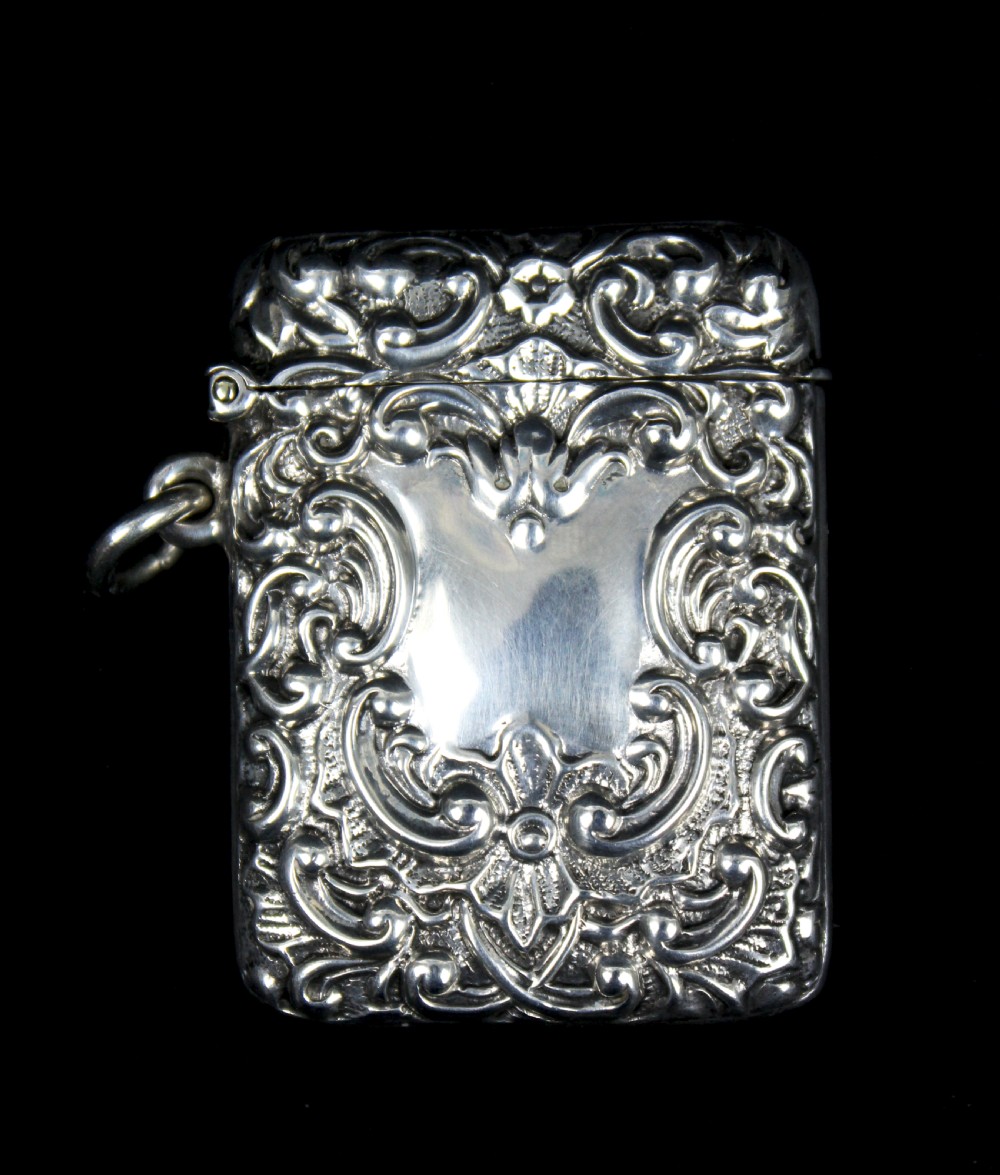 An ornate rectangular sterling silver Vesta case featuring embossed scrollwork and a central engraved cartouche with initials. View II