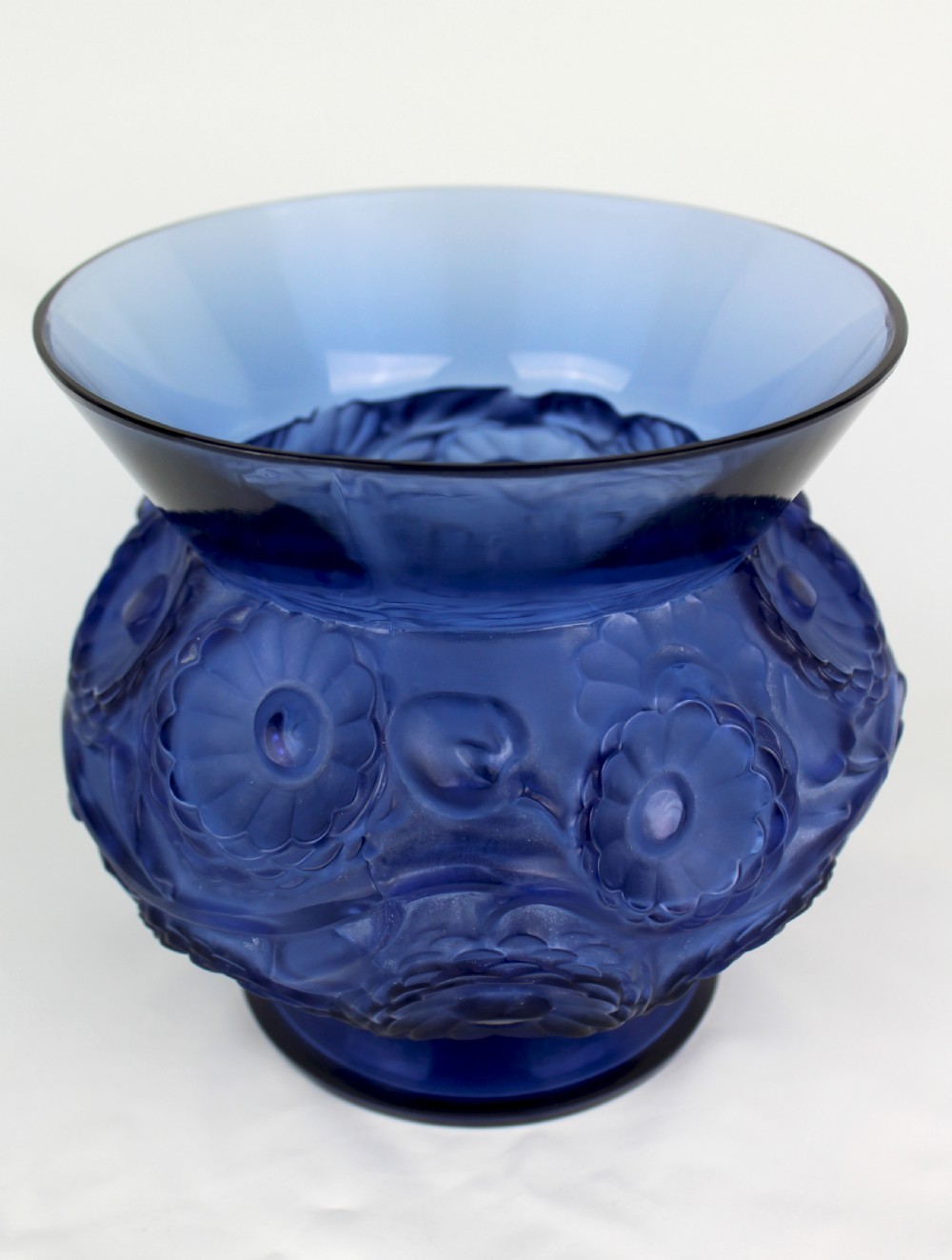 A cobalt blue glass vase with a flared circular rim and a rounded lower body featuring moulded marigold flower designs in relief.