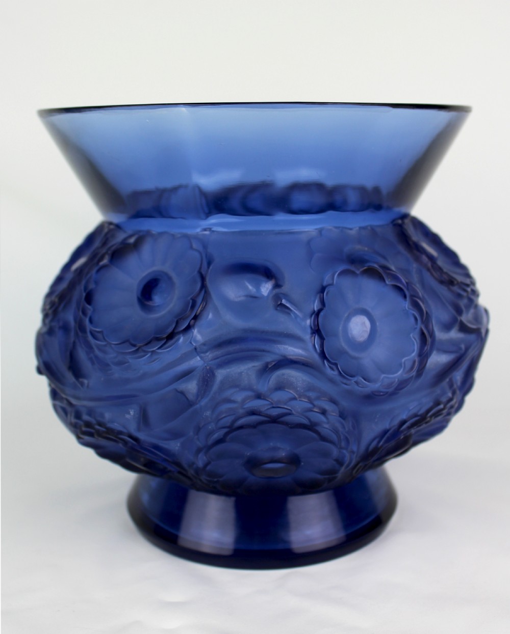 A cobalt blue glass vase with a flared circular rim and a rounded lower body featuring moulded marigold flower designs in relief. View II