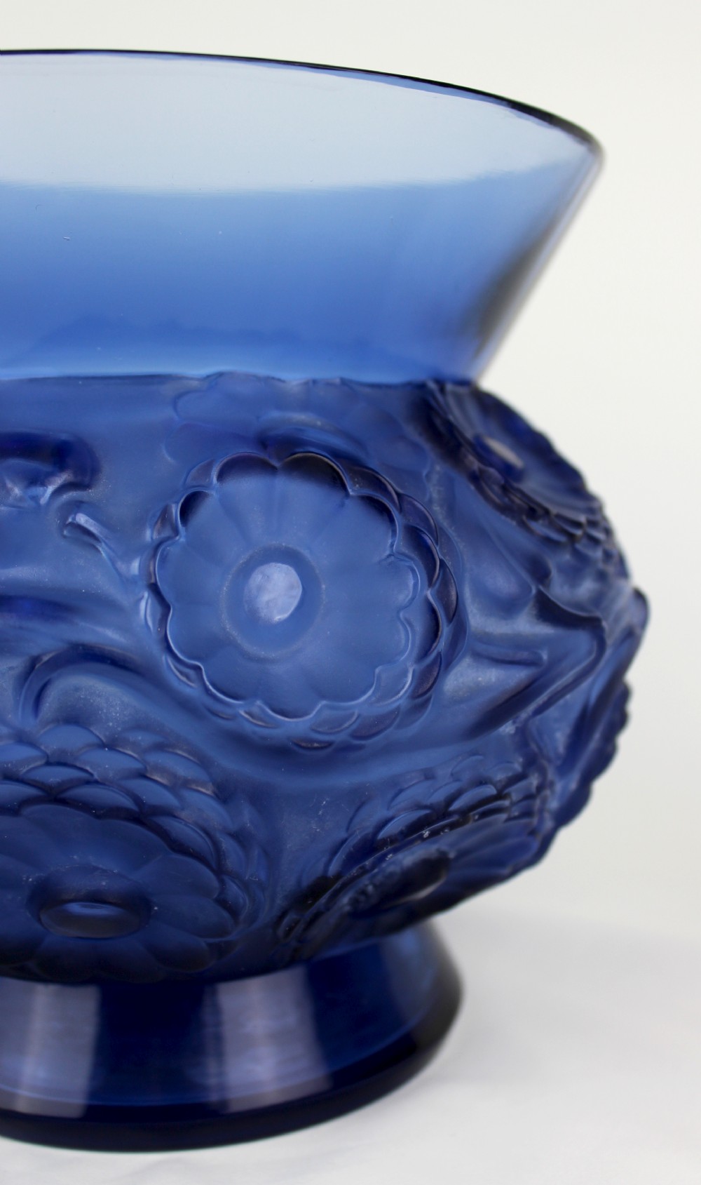A cobalt blue glass vase with a flared circular rim and a rounded lower body featuring moulded marigold flower designs in relief. View III