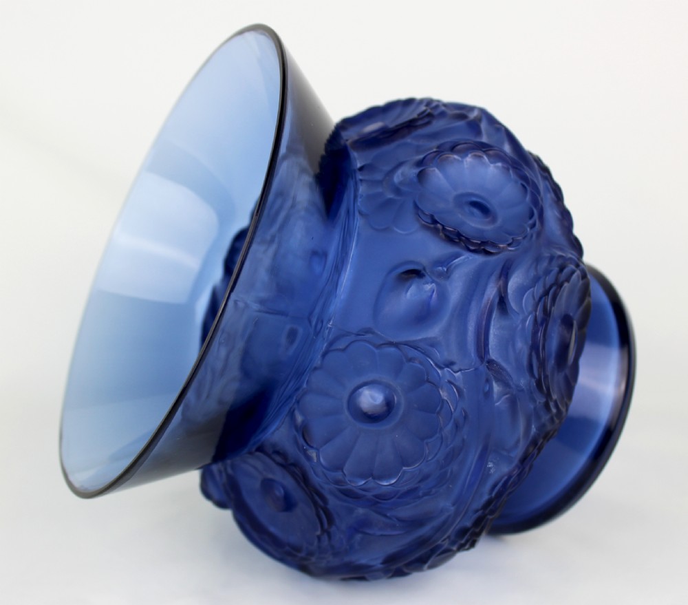 A cobalt blue glass vase with a flared circular rim and a rounded lower body featuring moulded marigold flower designs in relief. View IV