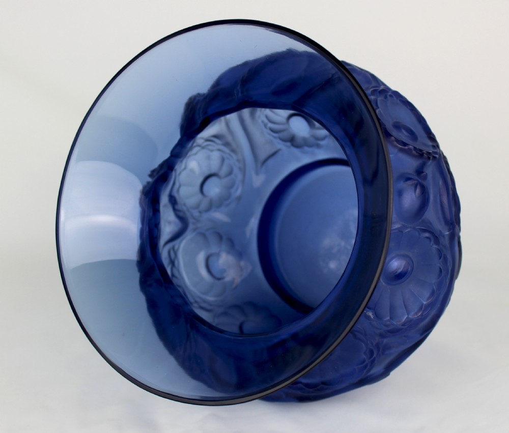 A cobalt blue glass vase with a flared circular rim and a rounded lower body featuring moulded marigold flower designs in relief. View V