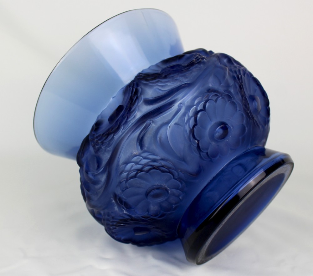 A cobalt blue glass vase with a flared circular rim and a rounded lower body featuring moulded marigold flower designs in relief. View VI