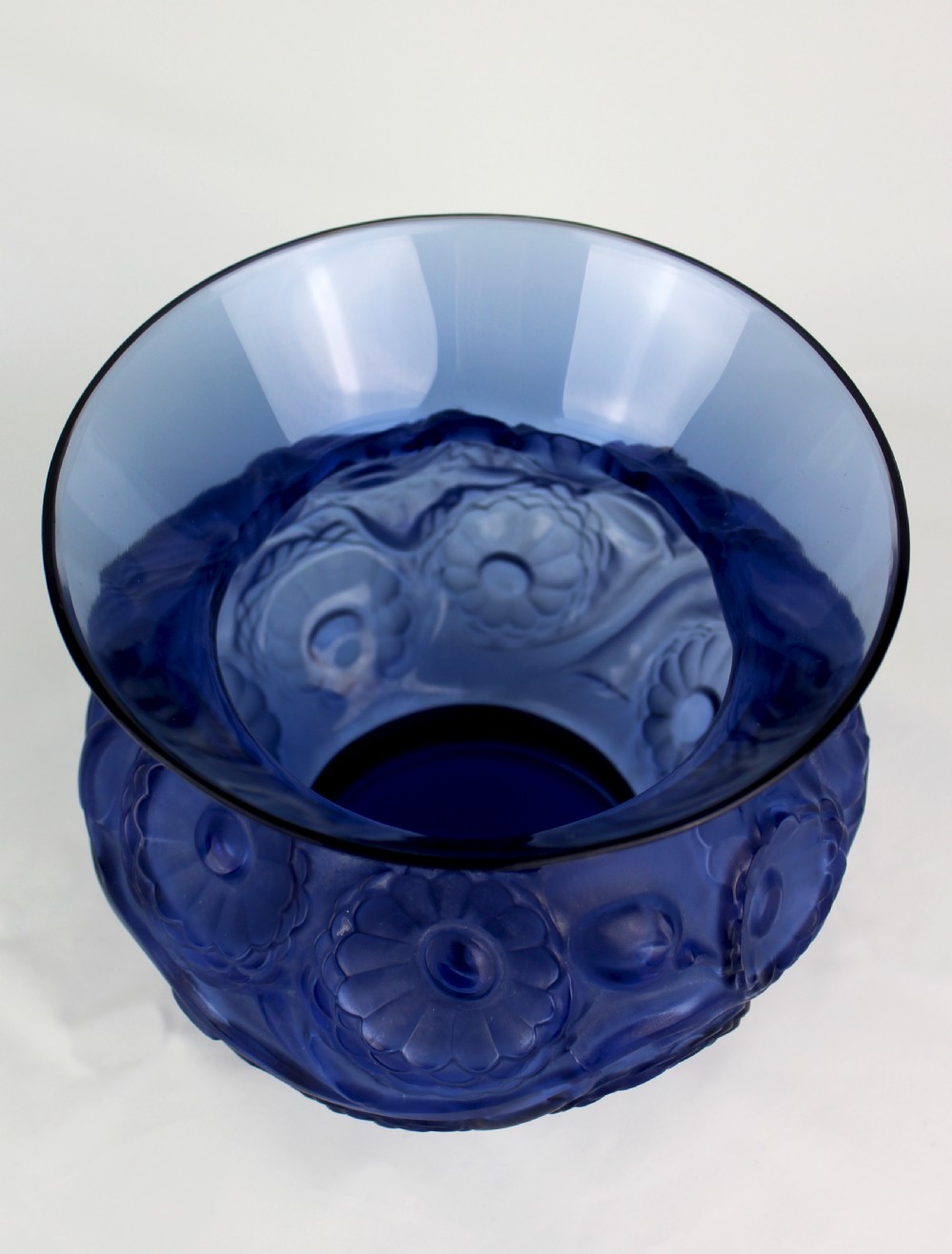 A cobalt blue glass vase with a flared circular rim and a rounded lower body featuring moulded marigold flower designs in relief. View VII