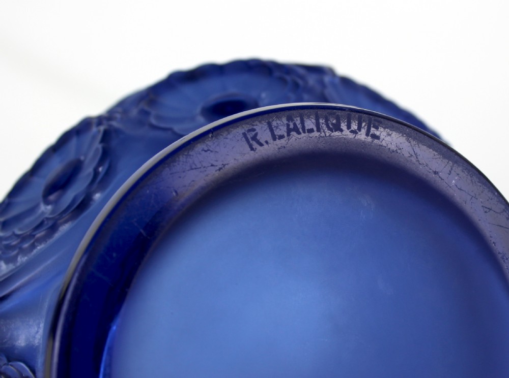 A cobalt blue glass vase with a flared circular rim and a rounded lower body featuring moulded marigold flower designs in relief. View VIII