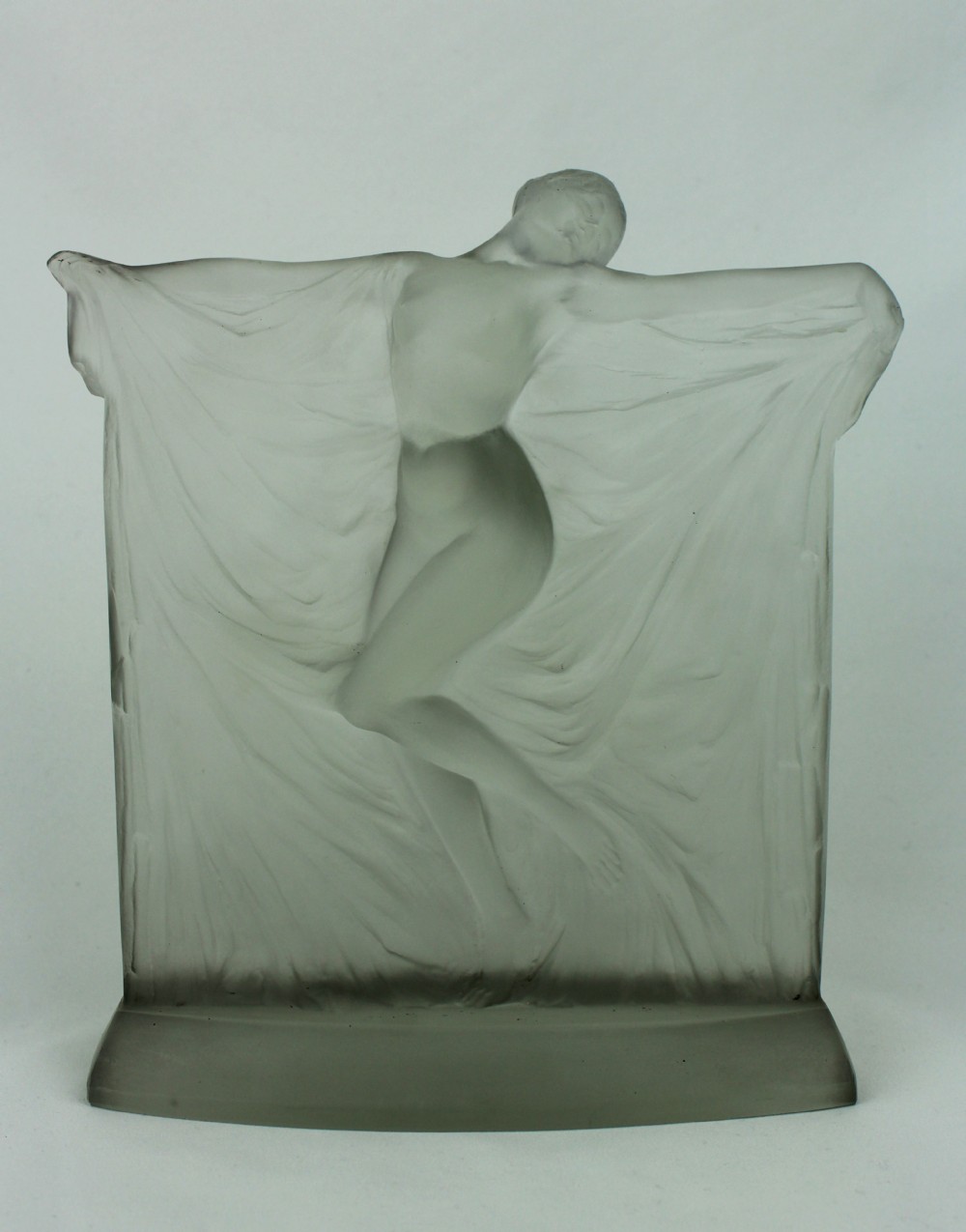 A frosted glass Art Deco statuette depicting a female figure with outstretched arms holding flowing drapery on a curved base.