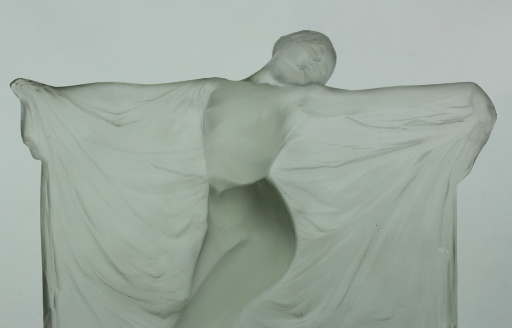 A frosted glass Art Deco statuette depicting a female figure with outstretched arms holding flowing drapery on a curved base. View II
