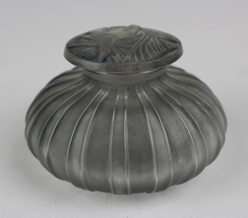 A ribbed frosted grey glass scent bottle featuring a round flat stopper moulded with butterfly relief details. View III