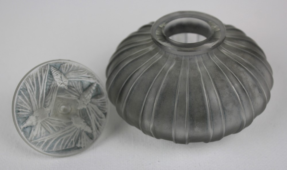 A ribbed frosted grey glass scent bottle featuring a round flat stopper moulded with butterfly relief details. View V
