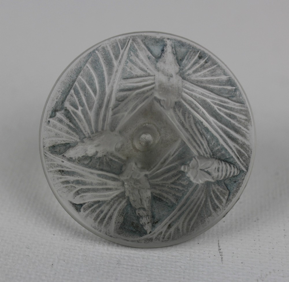 A ribbed frosted grey glass scent bottle featuring a round flat stopper moulded with butterfly relief details. View VI