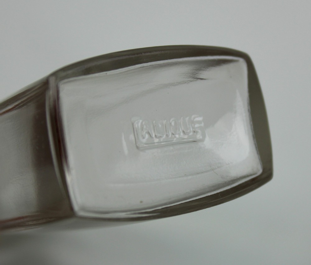 A clear glass Art Deco perfume bottle with a tapered rectangular body and a green frosted glass stopper decorated with a carved leaf pattern. View V