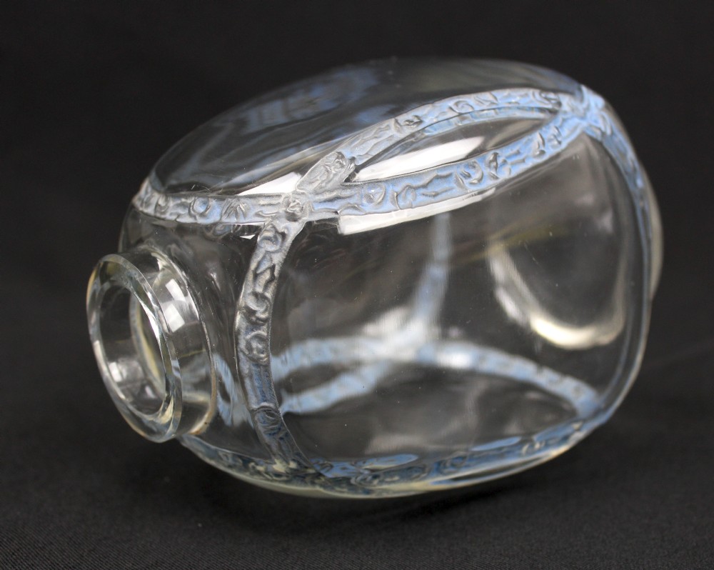 A clear moulded glass vase featuring intersecting blue patinated floral garland bands around an ovoid body. View III