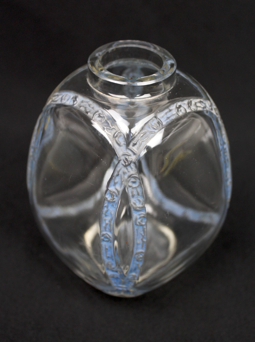 A clear moulded glass vase featuring intersecting blue patinated floral garland bands around an ovoid body. View IV