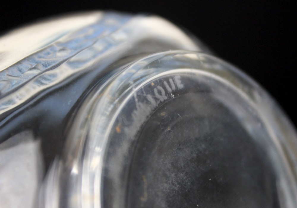 A clear moulded glass vase featuring intersecting blue patinated floral garland bands around an ovoid body. View V