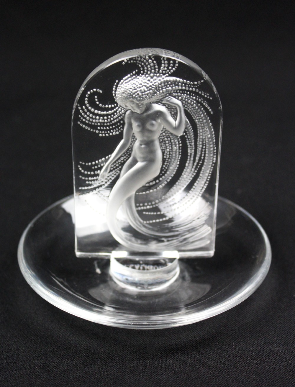 A clear glass pin dish featuring an upright arched centrepiece with a frosted glass relief depiction of a nymph surrounded by swirling beaded patterns. View V