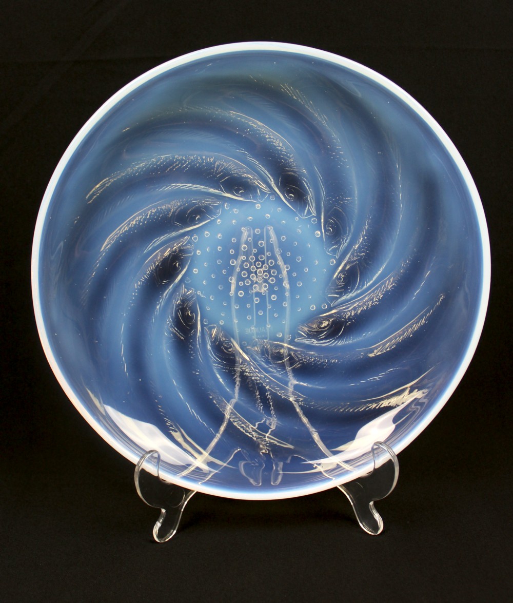 A circular Art Deco opalescent blue glass plate decorated with a swirling relief design of fish radiating from a central field of small raised bubbles. View II