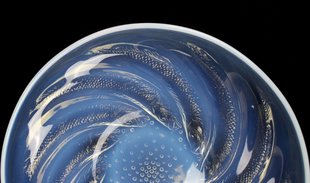 A circular Art Deco opalescent blue glass plate decorated with a swirling relief design of fish radiating from a central field of small raised bubbles. View III