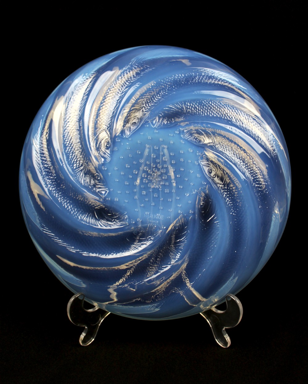 A circular Art Deco opalescent blue glass plate decorated with a swirling relief design of fish radiating from a central field of small raised bubbles. View VI