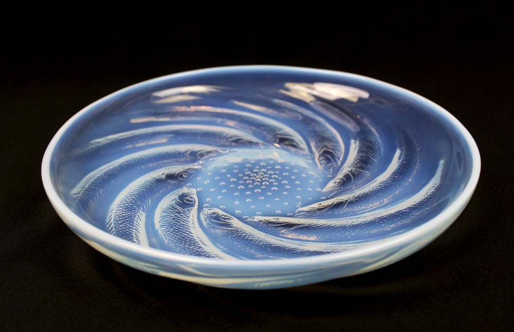 A circular Art Deco opalescent blue glass plate decorated with a swirling relief design of fish radiating from a central field of small raised bubbles. View VII