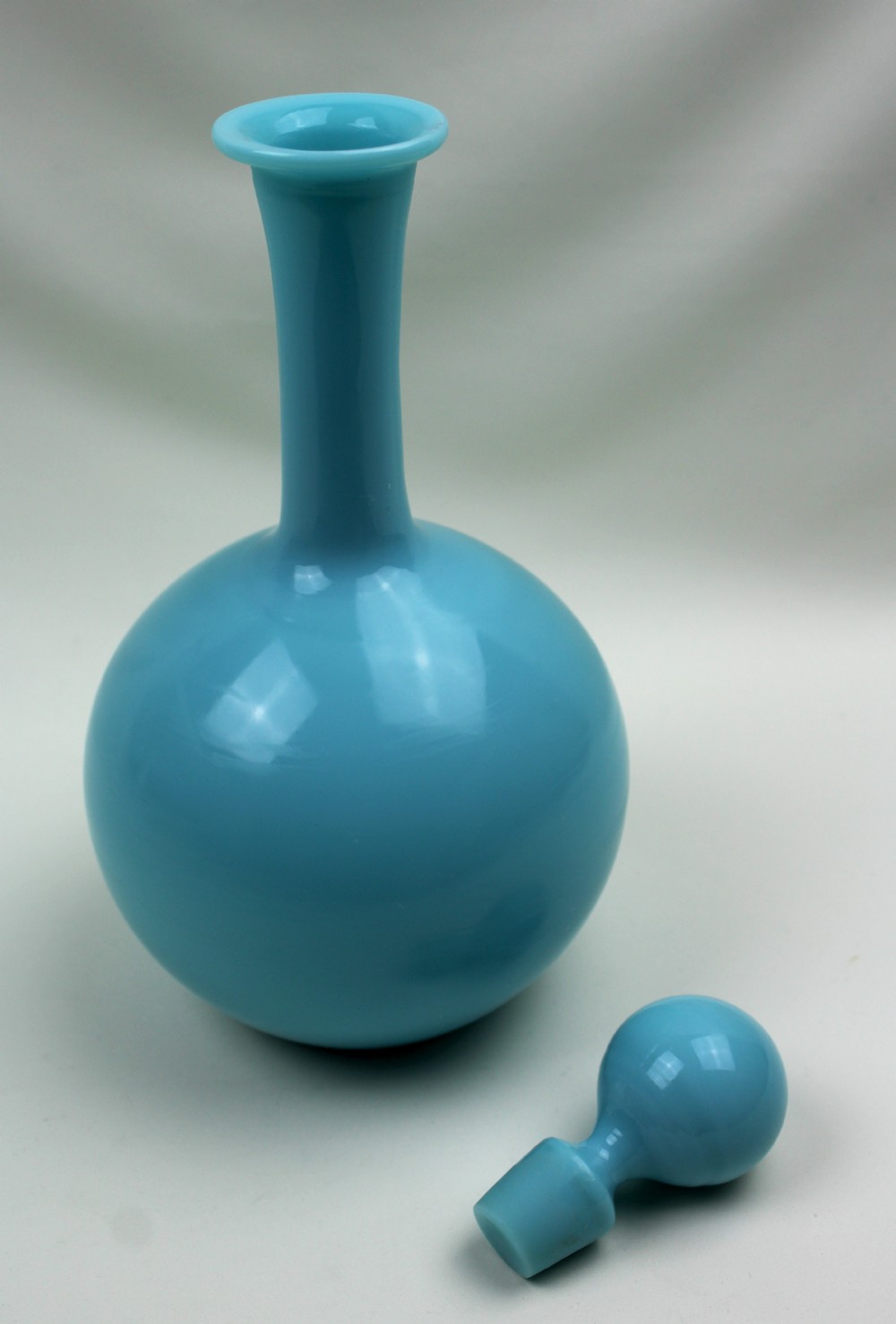 A turquoise blue opaline glass decanter featuring a spherical body, a long slender neck, a flanged rim, and a matching ball stopper. View II