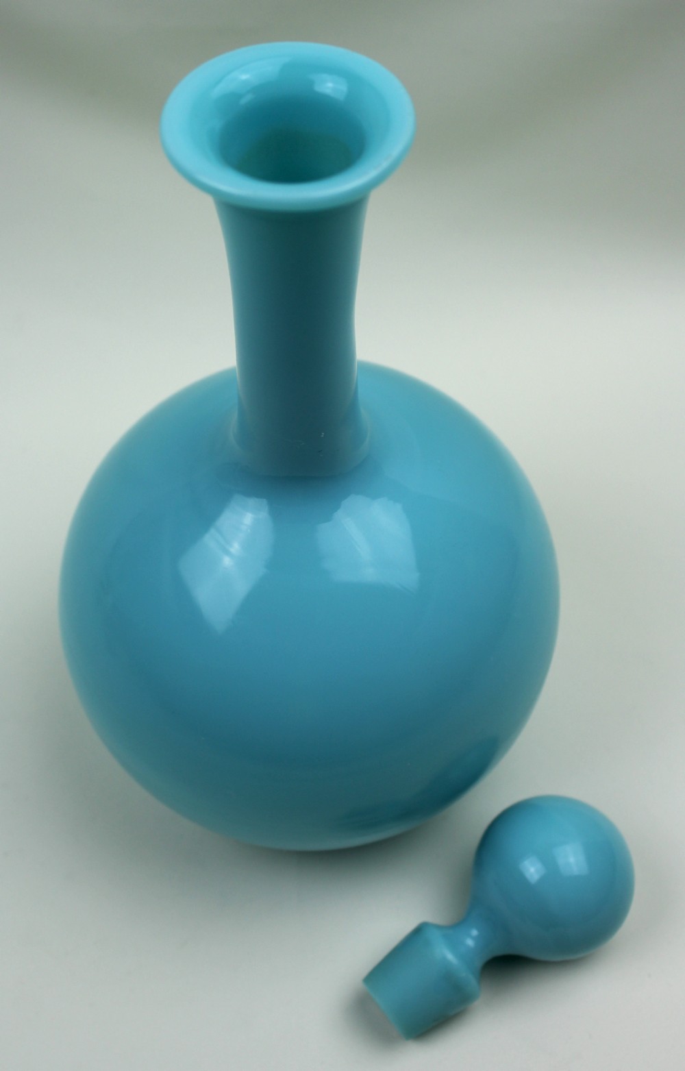 A turquoise blue opaline glass decanter featuring a spherical body, a long slender neck, a flanged rim, and a matching ball stopper. View III