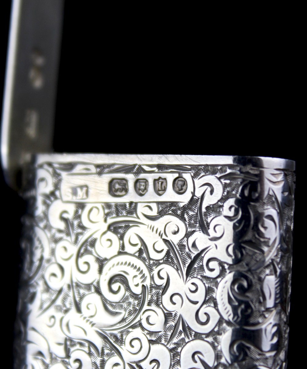 A rectangular sterling silver vesta case featuring hand-engraved foliate scrollwork and an unengraved circular central cartouche. View II