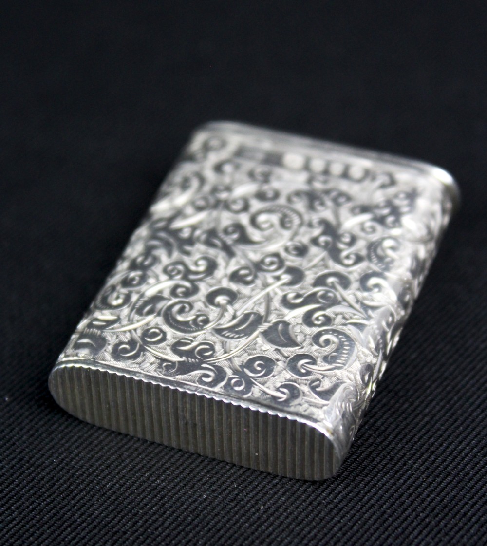 A rectangular sterling silver vesta case featuring hand-engraved foliate scrollwork and an unengraved circular central cartouche. View X