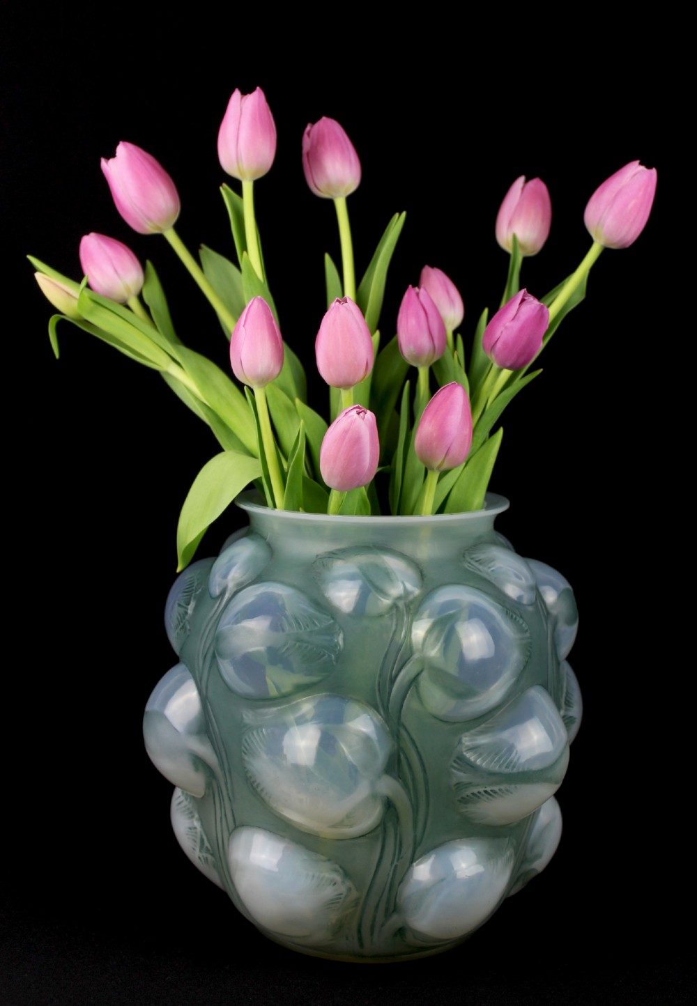 An Art Deco opalescent glass vase featuring high-relief moulded tulip buds and leaf detailing.