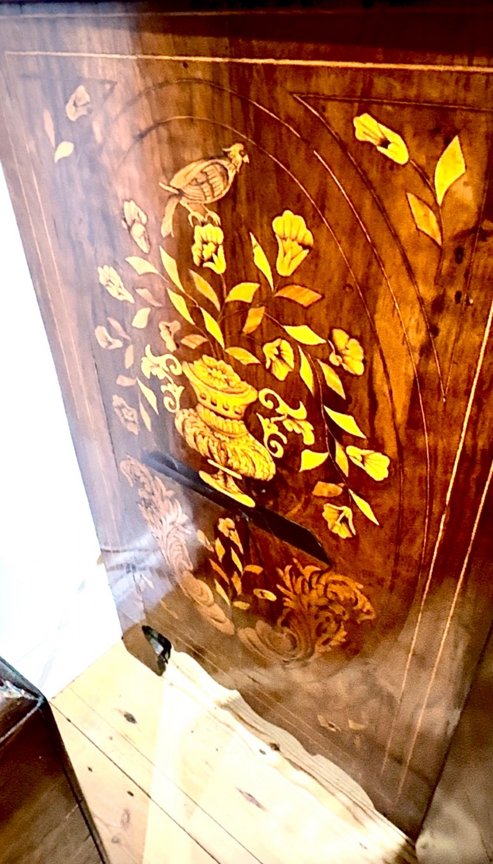 An antique Dutch walnut display cabinet featuring intricate floral wood marquetry, an arched glazed top, and a base with four drawers. View IV