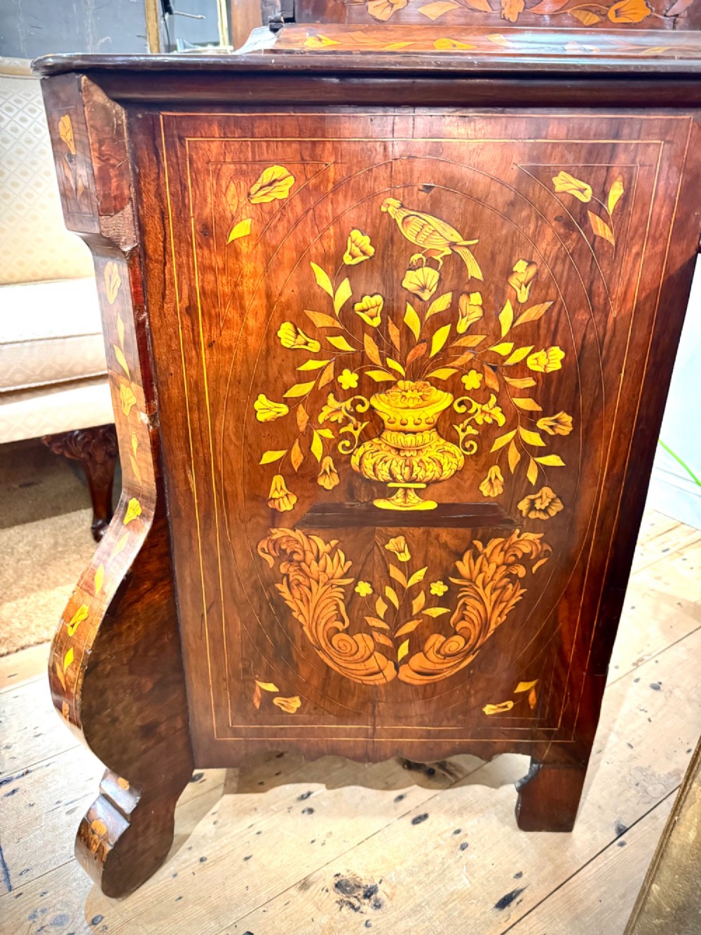 An antique Dutch walnut display cabinet featuring intricate floral wood marquetry, an arched glazed top, and a base with four drawers. View V