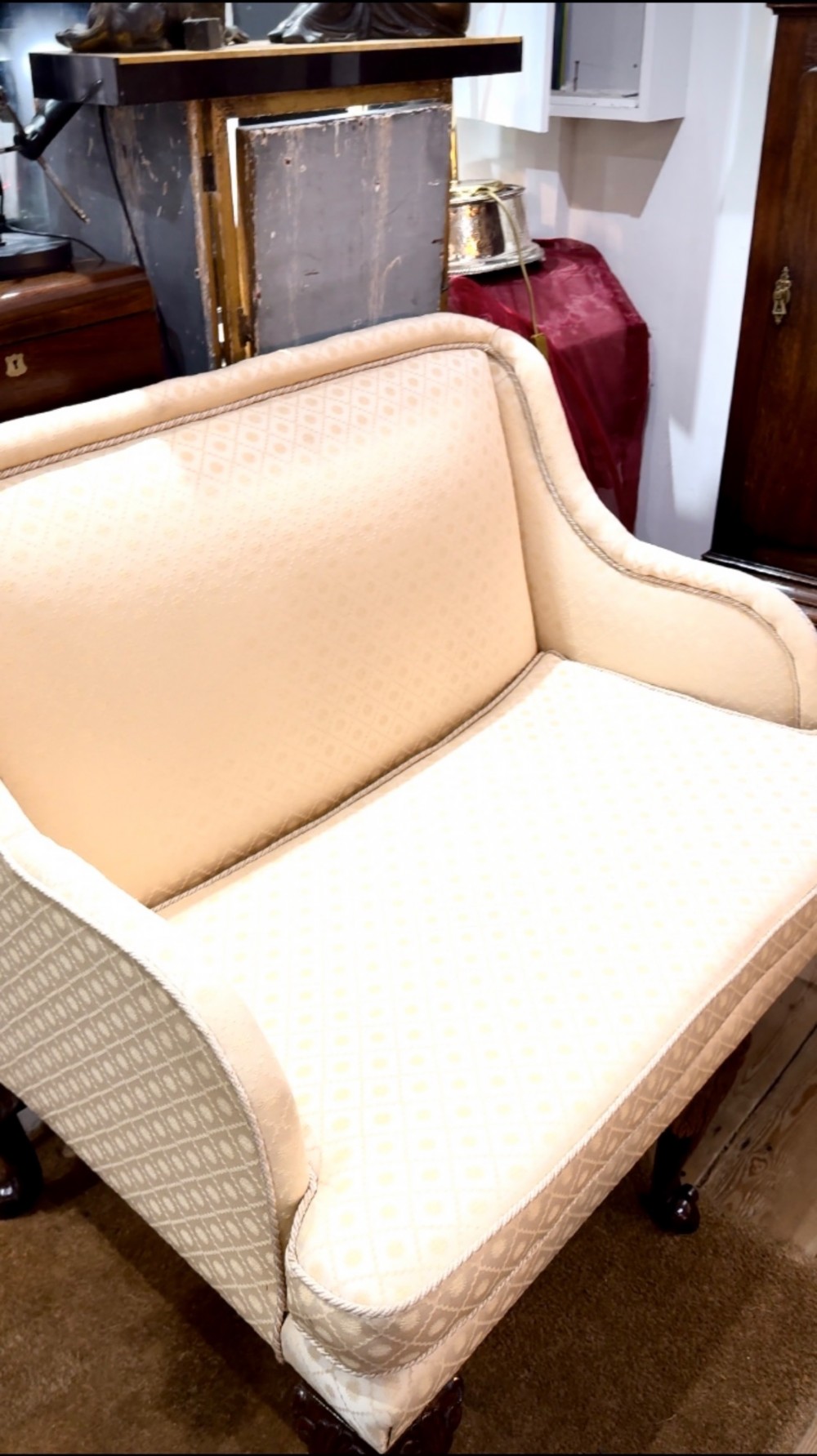 An Edwardian two-seater settee upholstered in cream geometric patterned fabric with piping trim and raised on dark carved mahogany cabriole legs. View V