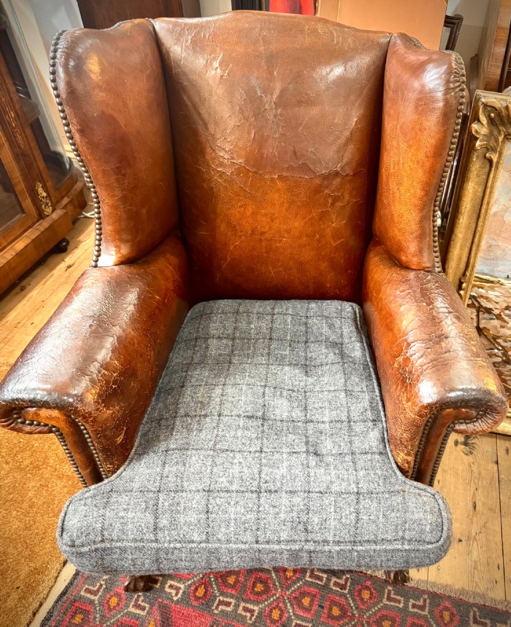 A late 19th-century Victorian wingback armchair upholstered in aged tan leather with brass studding and a textured grey tweed seat cushion. View III