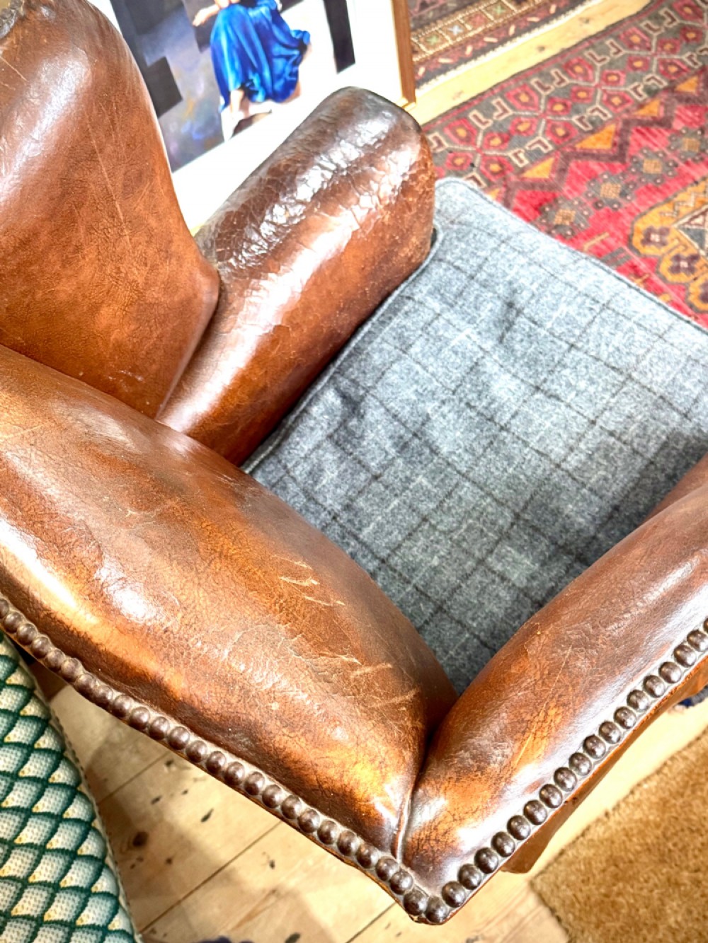 A late 19th-century Victorian wingback armchair upholstered in aged tan leather with brass studding and a textured grey tweed seat cushion. View IV