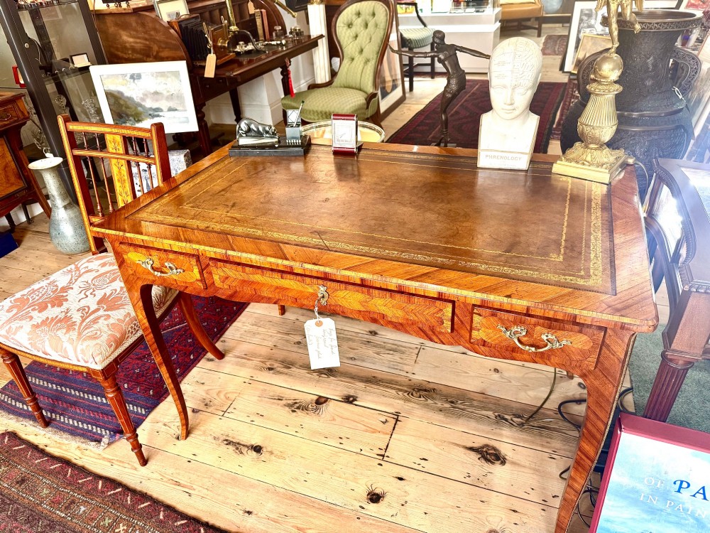 A French Louis XV style kingwood bureau desk featuring a gilt-tooled leather writing insert, parquetry veneer, drawer compartments with brass handles, and sweeping cabriole legs.