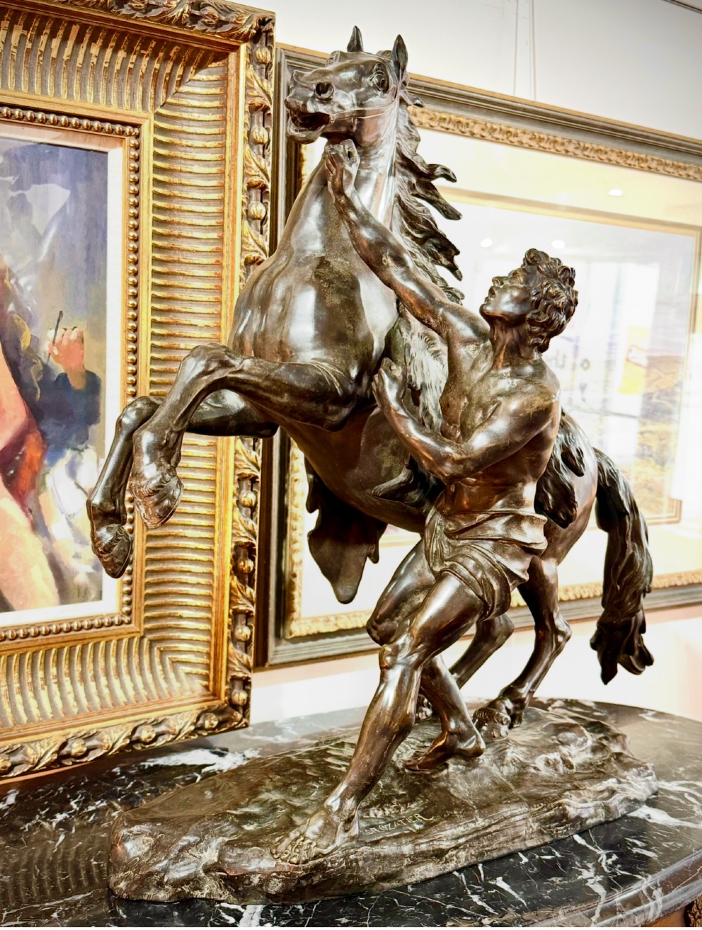 A dark patinated bronze sculpture depicting a rearing horse restrained by a groom, mounted on a naturalistic rocky base. View II
