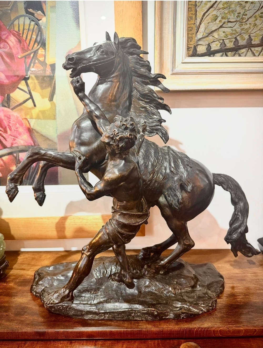 A dark patinated bronze sculpture depicting a rearing horse restrained by a groom, mounted on a naturalistic rocky base. View III