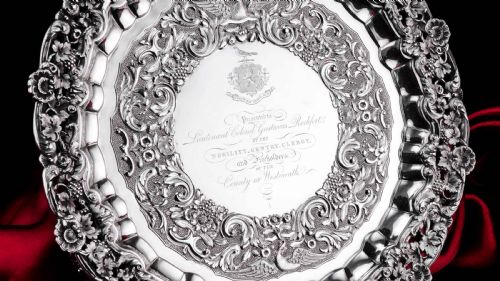fig 2. A circular Georgian sterling silver salver featuring an intricately detailed cast floral border and central inscription engraving.