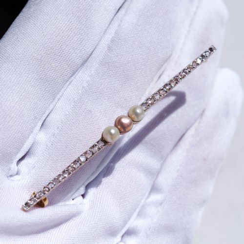 fig 4. An antique platinum and gold linear bar brooch set with diamonds and three central pearls, featuring a soft pink pearl in the centre.