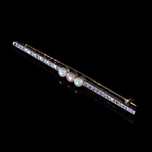 fig 3. An antique platinum and gold linear bar brooch set with diamonds and three central pearls, featuring a soft pink pearl in the centre.