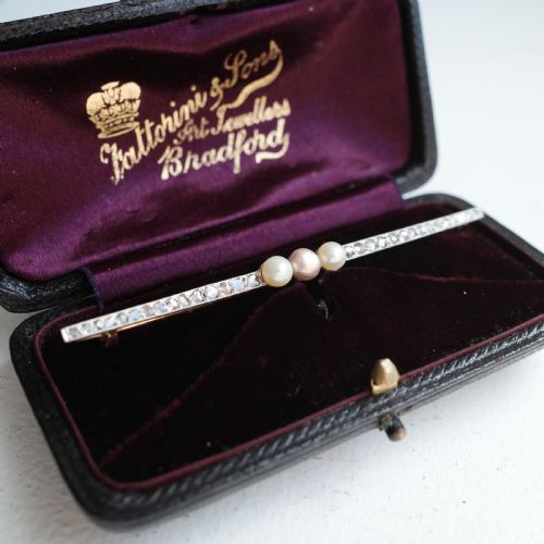 fig 1. An antique platinum and gold linear bar brooch set with diamonds and three central pearls, featuring a soft pink pearl in the centre.