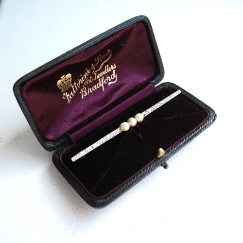 fig 2. An antique platinum and gold linear bar brooch set with diamonds and three central pearls, featuring a soft pink pearl in the centre.