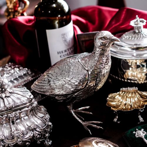 fig 4. A solid silver model of a partridge with chased feather detailing standing on two feet with a hinged compartment lid along its back.