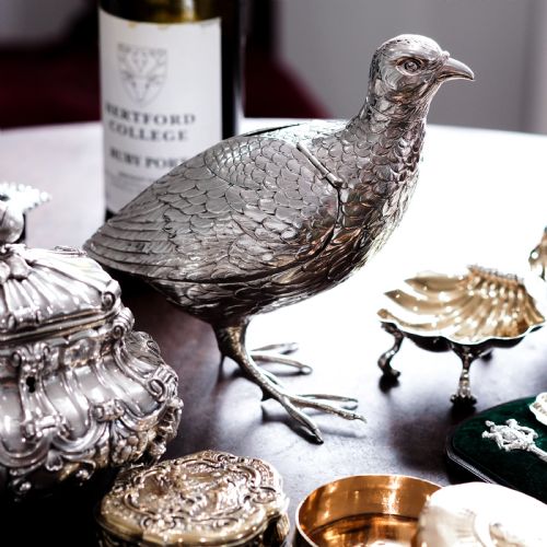 fig 9. A solid silver model of a partridge with chased feather detailing standing on two feet with a hinged compartment lid along its back.